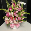 Pink and white floral arrangement in a white vase with a pink ribbon