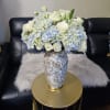 White roses and pale blue hydrangeas in a decorative vase