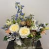 Mixed bouquet in a clear glass vase with cream roses and blue flowers