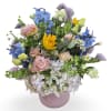 Mixed bouquet in a pink vase with blue, yellow, and pastel flowers