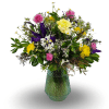 Mixed bouquet of yellow, pink, purple, and white flowers in a green glass vase