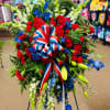 Large red, white, and blue floral standing spray with ribbon on an easel