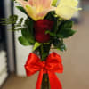 Bouquet of red roses and a pink lily in a glass vase with a red bow
