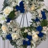 Heart-shaped floral wreath with blue and cream roses on a stand