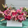 Pink roses and gerbera daisies arranged in a white box