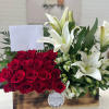 Red roses and white lilies arranged in a wooden box with a blank card