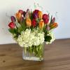 Colorful tulips arranged in a clear glass vase with white hydrangeas