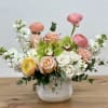 Mixed bouquet of pastel roses, ranunculus, and white blooms in a ceramic vase