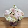 Blush pink roses and white peonies in a purple glass vase