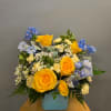 Yellow roses and blue flowers arranged in a light blue container