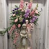 Tall floral arrangement with pink and purple blooms on a statue base