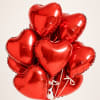 Cluster of red heart-shaped balloons tied with white ribbons