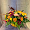 Mixed flower arrangement in a pumpkin-shaped container with autumn accents