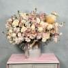Large pastel pink and cream flower arrangement in a white hatbox with a plush ballerina doll nestled among the blooms