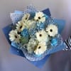 Hand-tied bouquet of white gerbera daisies and blue flowers wrapped in blue and polka dot paper