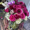 Bouquet of hot pink roses, orchids, and gerbera daisies in a glass vase