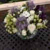 Bouquet of white roses, purple allium, and dark calla lilies in a glass vase