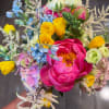 Colorful bouquet with pink peonies, yellow blooms, and blue flowers