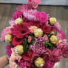 Pink bouquet with roses, chrysanthemums, orchids, and gold-wrapped chocolates