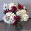 Bouquet of red roses, white orchids, and white hydrangeas in a glass vase