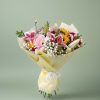 Mixed bouquet of pink, yellow, and white flowers wrapped in pale yellow paper