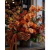 Autumn floral arrangement with orange orchids and roses in a dark vase