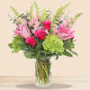 Pink lilies and roses with green hydrangea in a clear glass vase