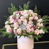 Pink roses and lisianthus in a pale pink hat box with greenery