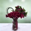 Deep burgundy calla lilies and purple flowers in a clear glass vase