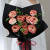 Bouquet of pink-and-cream roses wrapped in black paper with a red ribbon