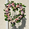 Heart-shaped floral wreath with pink and white flowers on a stand