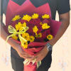 Bouquet of red roses and yellow daisies wrapped in burgundy paper