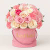 Pink and cream roses arranged in a pink hat box