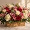 Mixed roses and hydrangeas arranged in a woven basket