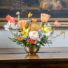 Mixed floral arrangement in a gold vase with orange, yellow, and white blooms