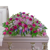 Large pink and purple floral casket spray on a light-colored casket