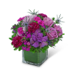 Purple and pink floral arrangement in a square glass vase