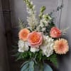 Peach roses and gerbera daisies in a glass vase with white blooms
