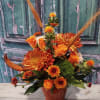 Orange floral arrangement in a red vase with chrysanthemums and roses