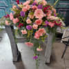 Large pink and purple floral arrangement on a wooden stand