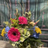 Bright mixed bouquet with pink gerbera daisies and blue and yellow blooms in a vase