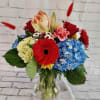 Mixed bouquet with hydrangeas, roses, gerbera daisies, and amaryllis in a glass vase
