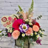 Mixed bouquet in a wooden box with pink, peach, and purple flowers