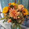 Bouquet of sunflowers, peach dahlias, and roses in a glass vase