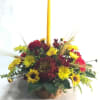 Basket arrangement of yellow and red flowers with a tall yellow candle