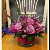 Pink roses and purple flowers arranged in a round glass vase