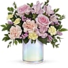 A bouquet arranged in a short cylinder vase of statice, greenery, roses
