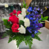 A blend of Red roses, white roses, blue delphinium and greens.