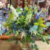 Mixed bouquet in a clear glass vase with blue, white, and yellow flowers