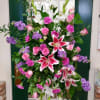 Tall floral spray with pink roses, white lilies, and purple blooms